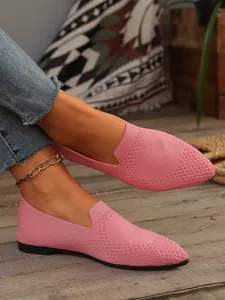 Nahaufnahme von rosa flach gespitzten Slipper-Schuhen für Damen auf rustikalem Holzboden
