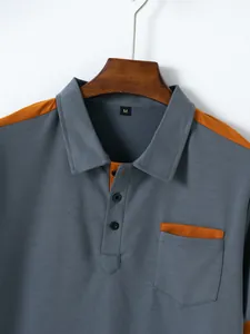 Close-up detail of men's color-block casual polo shirt with chest pocket on a hanger