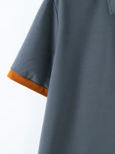 Close-up detail of grey men's casual polo shirt with orange contrast sleeve cuff