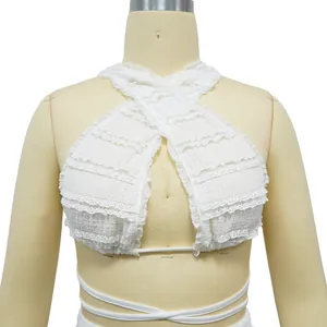 Detail view of white lace halter crop top with cross-front design and ruffle edges.