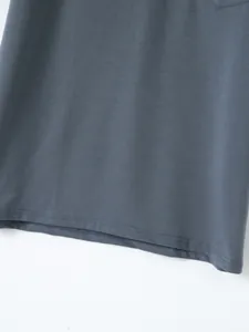 Close-up showing the high-quality stitching and smooth fabric of the dark grey polo shirt hem.