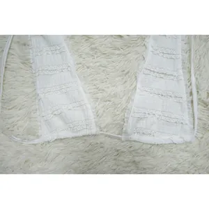 Close-up detail of white lace halter dress with textured tiered ruffles and ties.