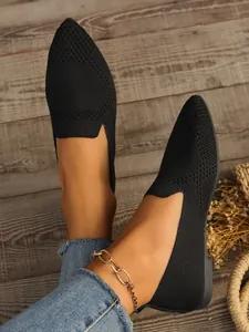 Nahaufnahme von schwarzen, spitz zulaufenden Strick-Ballerinas mit Webmuster