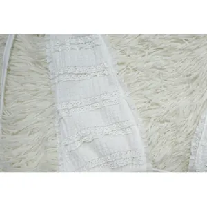 Detailed macro view of white tiered lace ruffles and textured gauze fabric on dress