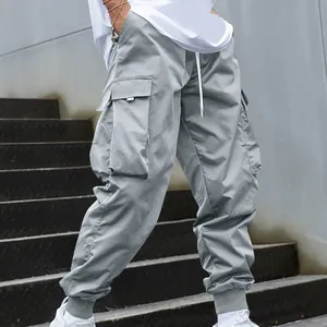 Detail view of grey loose-fit cargo jogger pants with large side pockets on model