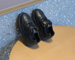Vista detallada de zapatillas negras para niños con cierre de velcro sobre mesa de madera