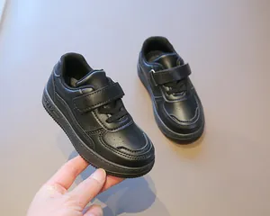 Vista detallada de zapatillas negras para niños con tiras de velcro y parte superior de cuero