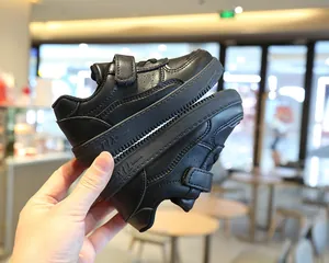 Vista lateral de zapatos negros para niños con cierre de velcro y logo TIX en la suela
