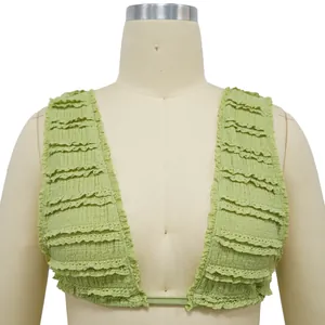 Close-up detail of light green ruffled crop top with lace edge on mannequin