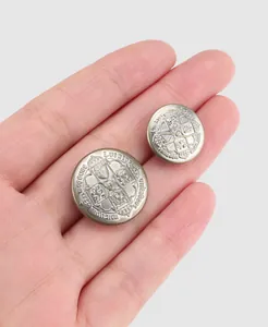 Macro view of two vintage brass buttons featuring intricate crown crest engravings