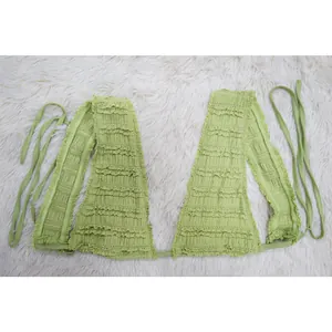 Light green lace textured ruffled sleeveless tie-back crop top laid flat on white fur