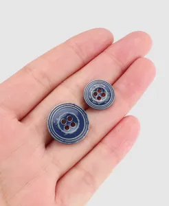 Close-up detail of vintage blue distressed metal four-hole buttons on a palm for scale