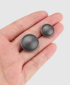 Close-up detail of textured vintage silver brass clothing buttons held in hand