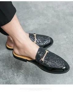 Close-up view of men's black glitter half slippers featuring a gold horsebit buckle