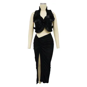 Dettaglio di un set a due pezzi plissettato nero con crop top a volant e gonna a spacco