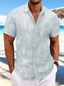 Men's light blue tie-dye short sleeve beach shirt styled in a tropical seaside setting.