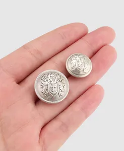 Close-up detail of high-quality brass suit buttons with embossed heraldic anchor design.