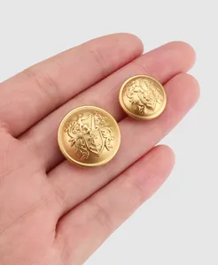Nahaufnahme von hochwertigen goldenen Messingknöpfen mit Wappenprägung in der Hand