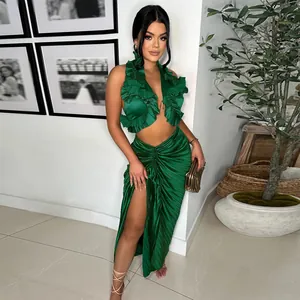 Dettaglio di un set verde smeraldo con top a balze e gonna lunga a pieghe con spacco alto laterale.
