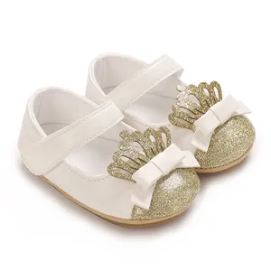 Detailansicht der weißen Baby-Prinzessinenschuhe mit goldener Krone und Schleife