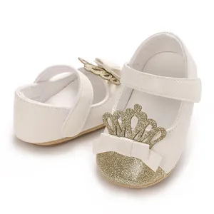 Nahaufnahme weißer Babyschuhe für Mädchen mit goldener Glitzerkrone und Schleife