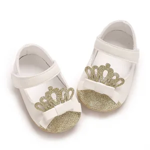 Detailaufnahme der weißen Lauflernschuhe für Babys mit goldener Glitzerkrone und Schleife