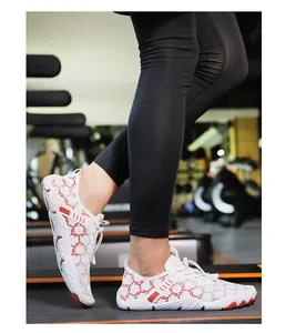 Dettaglio di scarpe da acqua bianche con motivo esagonale rosso su tapis roulant