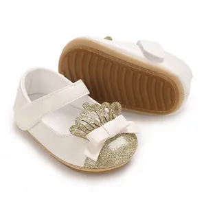 Detailaufnahme von Baby-Lauflernschuhen mit goldener Krone und Glitzerschleife