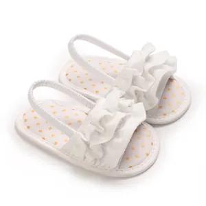 Detailed view of white baby girl walking sandals with ruffle strap and gold dots