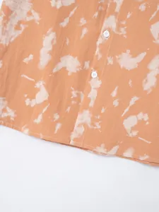 Close-up detail of a men's orange tie-dye beach shirt featuring fabric texture and white buttons