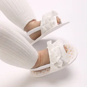 Close-up of white baby ruffled sandals with elastic back strap and yellow polka dot insole