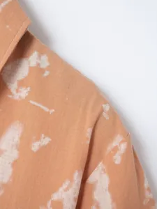 Detailed close-up of orange and white tie-dye men's beach shirt fabric texture