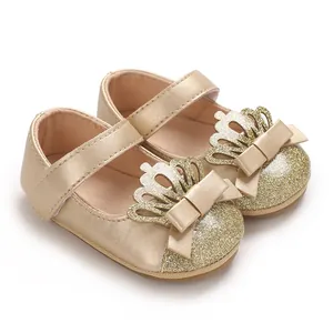 Nahaufnahme goldener Lauflernschuhe für Babys mit Kronen- und Glitzerschleifen-Design