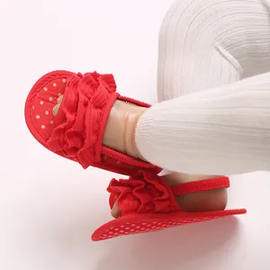 Detailed macro view of red ruffled baby girl walking sandals with soft sole and gold dots.