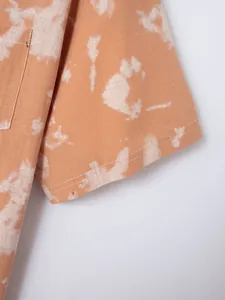Close-up detail of orange tie-dye pattern and stitching on short sleeve shirt