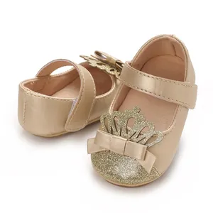 Nahaufnahme von goldenen Baby-Lauflernschuhen mit funkelnder Krone und einer Schleife