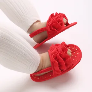 Detail view of red baby girl sandals with ruffles and golden polka dot soft sole.