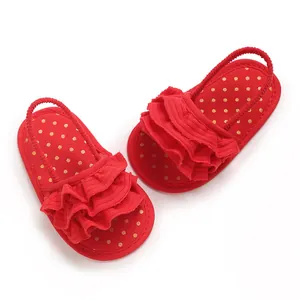 Macro detail of red baby girl ruffled sandals with gold polka dots and flexible sole.