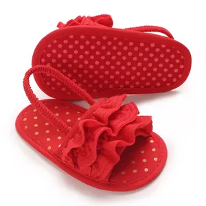 Detail view of red ruffled baby sandals with soft soles and gold polka dots.