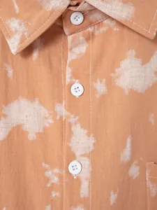 Close-up of orange tie-dye men's casual beach shirt with white buttons and collar detail.