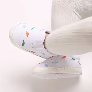 Close-up of baby boy soft-sole pre-walker shoes with colorful dinosaur prints