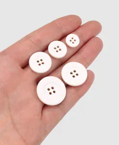Macro view of eco-friendly ivory white cotton buttons in various sizes held in hand