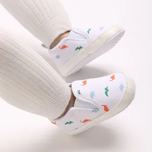 Detail view of baby walking shoes with colorful dinosaur patterns on infant feet