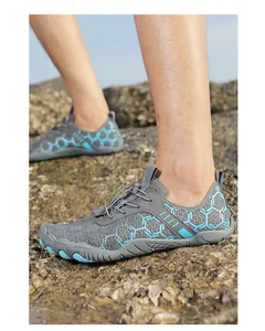 Dettaglio di scarpe da scoglio grigie e blu indossate su una riva rocciosa esterna