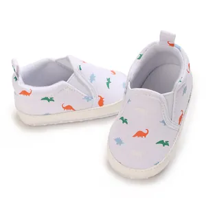 Infant white canvas walking shoes featuring colorful dinosaur patterns for baby boys