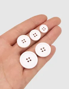 Macro view of five white four-hole eco-friendly cotton buttons held in human palm