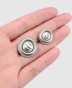 Close-up of silver metal suit buttons with decorative rope border held in a hand