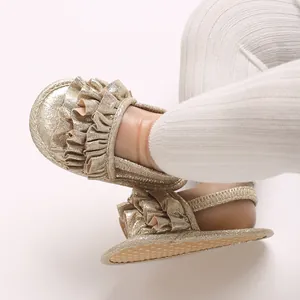 Close-up detail of infant girl gold ruffled sandals featuring soft breathable soles