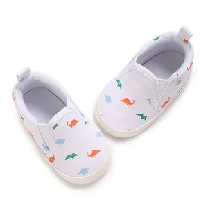 Detailed top-down view of white baby boy slip-on walking shoes with colorful dinosaur prints
