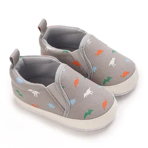 Detail of grey baby boy walking shoes featuring colorful dinosaur print and soft sole